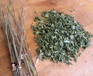 A pile of dried herb leaves sitting next to a pile of bare herb stems.