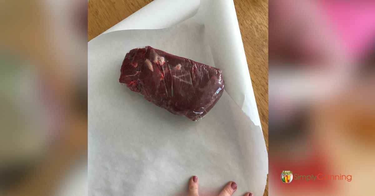 Wrapping a piece of plastic wrapped meat in freezer or butcher paper.