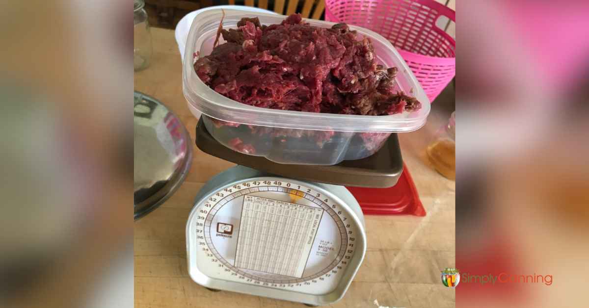 Weighing ground meat on a kitchen scale.