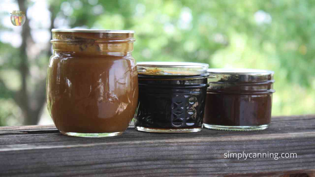 Three small jars filled with various kinds of fruit butter.