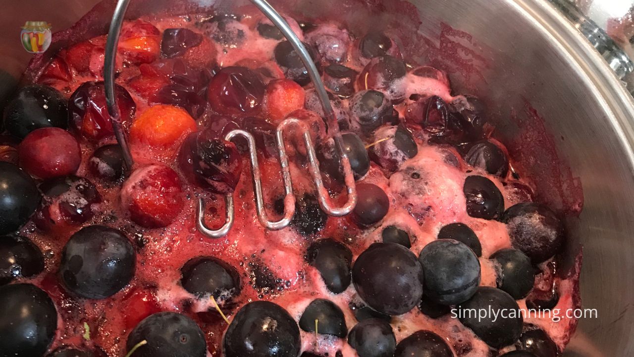 Smashing plums in their own cooking liquid.