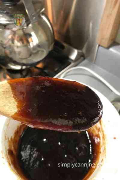 Thick plum butter mounding up on the spoon.