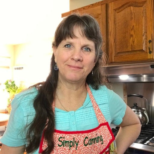 Sharon in her kitchen wearing a red Simply Canning apron.